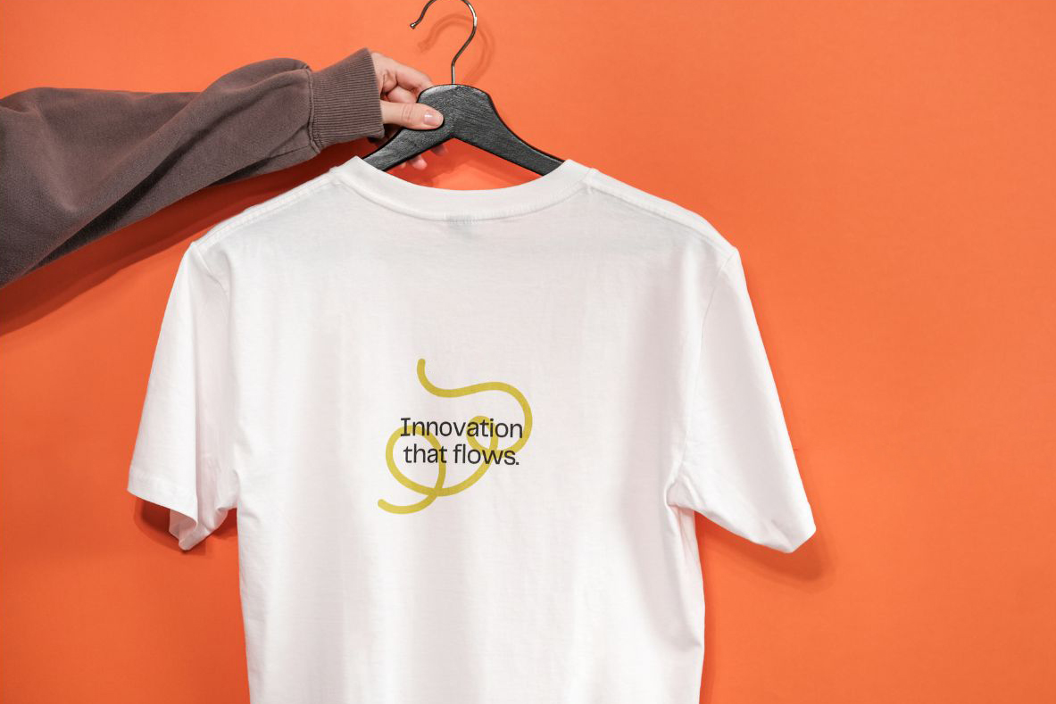 White custom-printed T-shirt on hanger with the words “Innovation that flows,” representing Zamar’s personalized screen printing quality and design options.