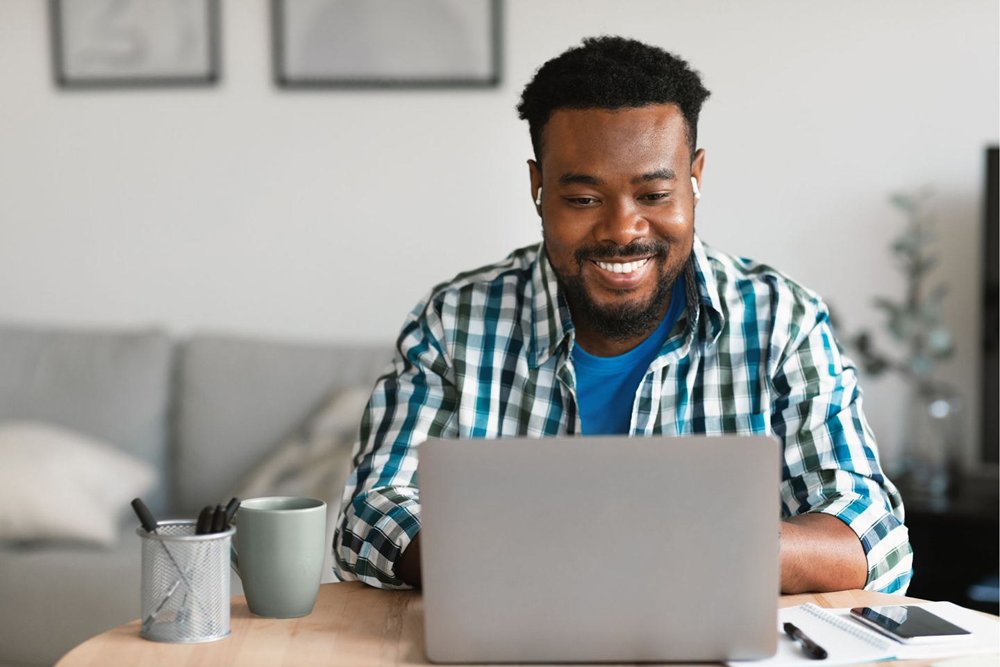 Smiling trade professional using a laptop to order work uniforms through a custom online store.